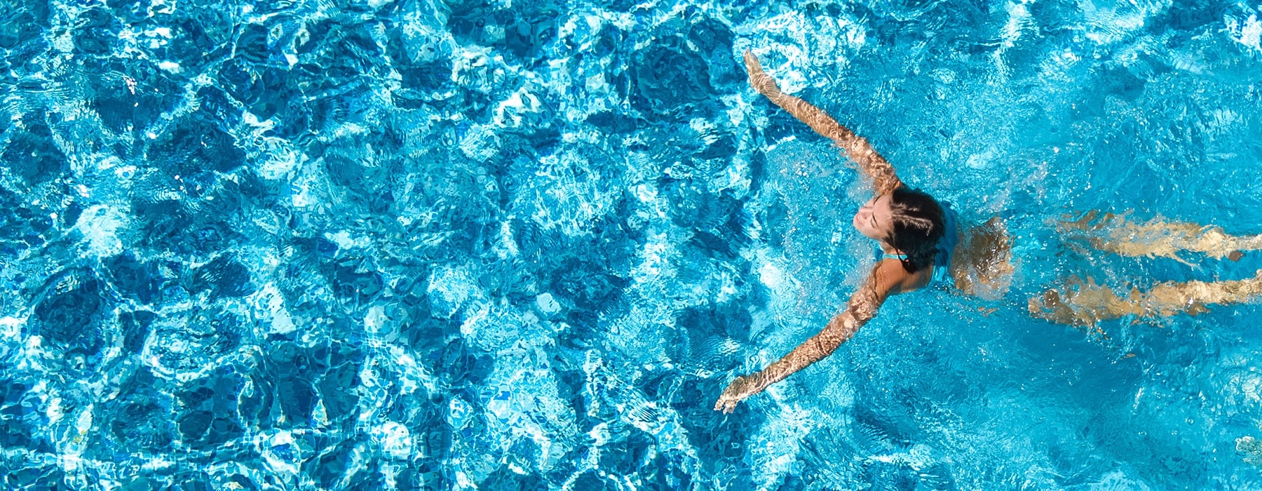 lifestyle image of a woman swimming in a large pool